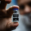Hand holding a small vial labeled 'GHRP-6' with a blurred background